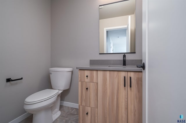 half bath with toilet, vanity, and baseboards