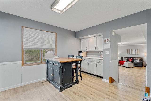 1200 Crestview Dr, Vermillion, SD 57069 - kitchen featuring white cabinets, light wood-style flooring, a desk, and baseboards