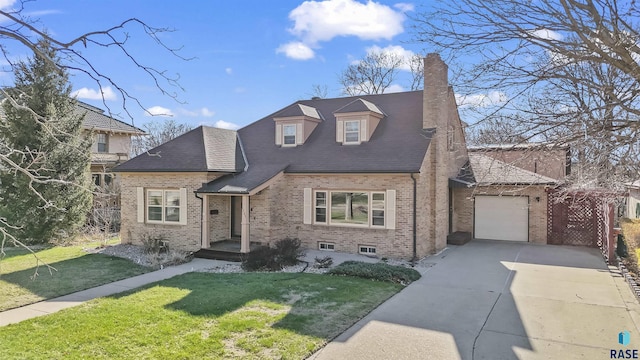 1205 Douglas Ave, Yankton, SD 57078 - view of front of house featuring a chimney, driveway, an attached garage, a front yard, and brick siding