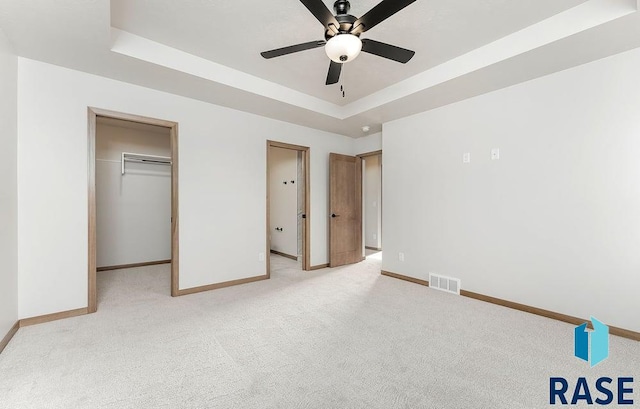 5709 S Spirea Ave, Sioux Falls, SD 57106 - unfurnished bedroom featuring a tray ceiling, a spacious closet, visible vents, light carpet, and baseboards