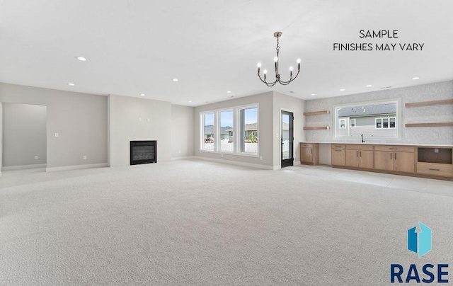 8312 E Wicker Ct, Sioux Falls, SD 57110 - unfurnished living room featuring a glass covered fireplace, recessed lighting, a sink, baseboards, and a notable chandelier
