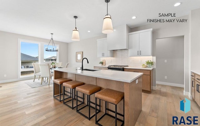 8312 E Wicker Ct, Sioux Falls, SD 57110 - kitchen featuring tasteful backsplash, custom exhaust hood, a kitchen breakfast bar, gas range, and a sink