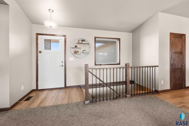 foyer entrance with a healthy amount of sunlight, visible vents, baseboards, and wood finished floors