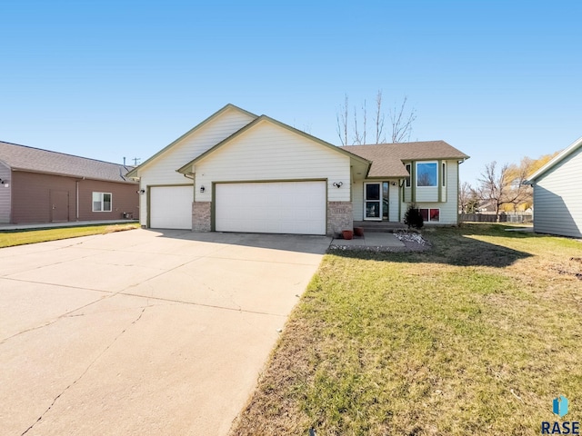 split level home with roof with shingles, a front yard, brick siding, a garage, and concrete driveway