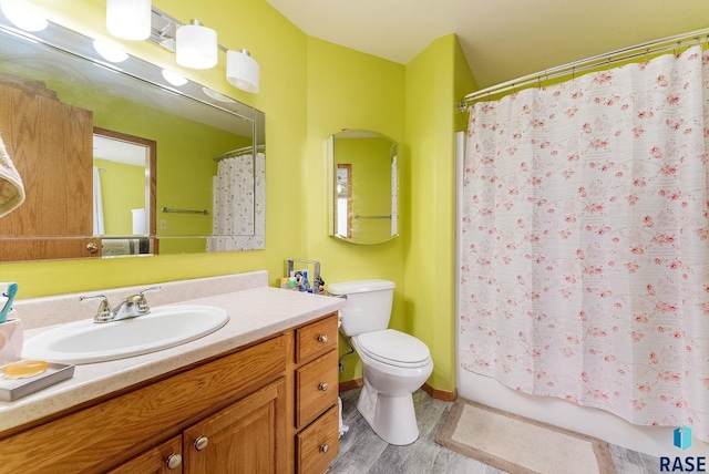 full bath with toilet, wood finished floors, vanity, and shower / bathtub combination with curtain