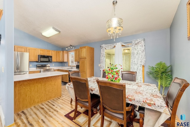 dining room featuring light wood finished floors and vaulted ceiling