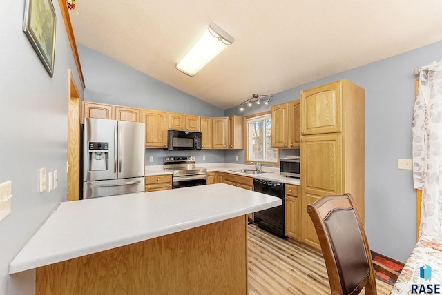 kitchen with a peninsula, black appliances, lofted ceiling, light wood finished floors, and a sink