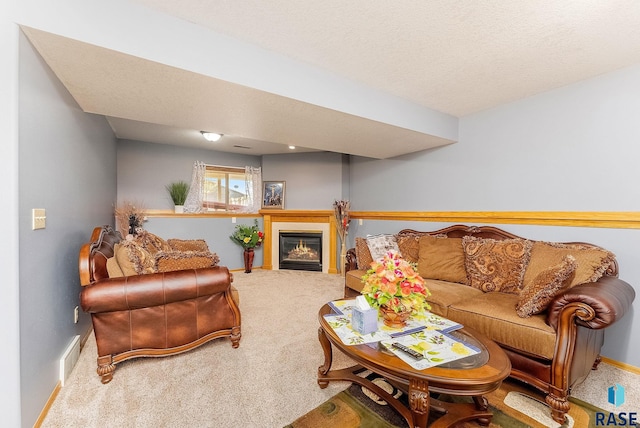 carpeted living area with visible vents, baseboards, a glass covered fireplace, and a textured ceiling