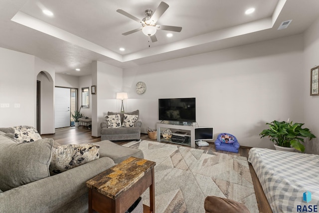 living area featuring a ceiling fan, visible vents, recessed lighting, wood finished floors, and a raised ceiling