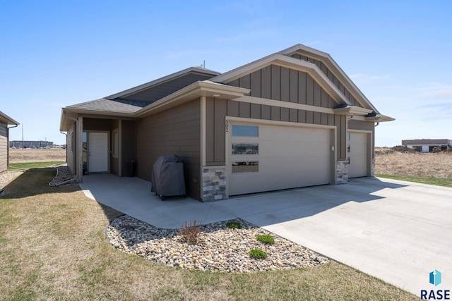 view of side of home featuring a garage, board and batten siding, stone siding, and concrete driveway
