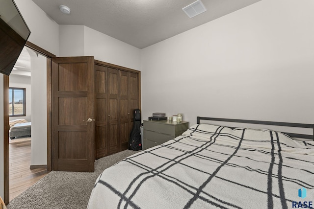 bedroom with visible vents, a closet, and wood finished floors