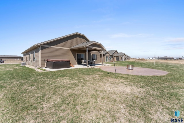 back of property featuring a lawn, a patio, and a hot tub