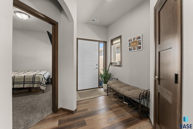 entryway featuring arched walkways, visible vents, baseboards, and wood finished floors