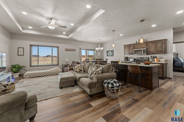 living room featuring a textured ceiling, recessed lighting, wood finished floors, and ceiling fan with notable chandelier
