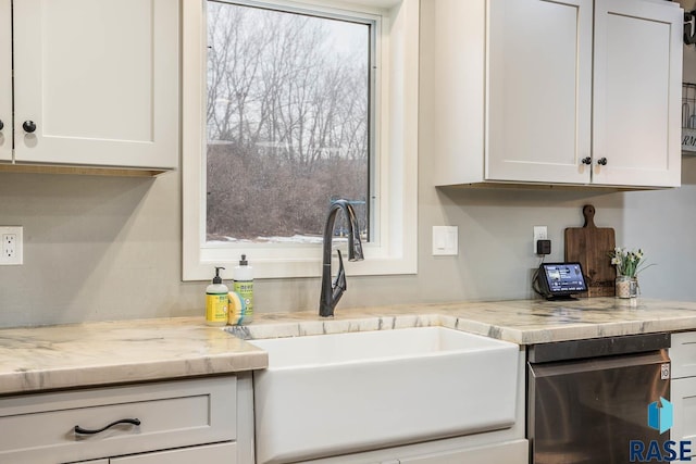 kitchen featuring stainless steel dishwasher, white cabinets, and a sink