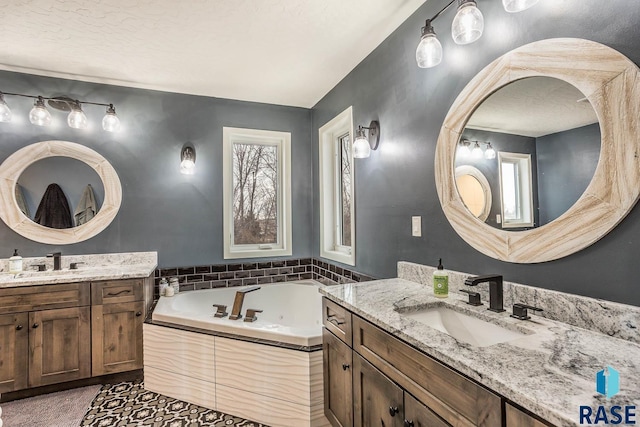bathroom with a bath, two vanities, and a sink
