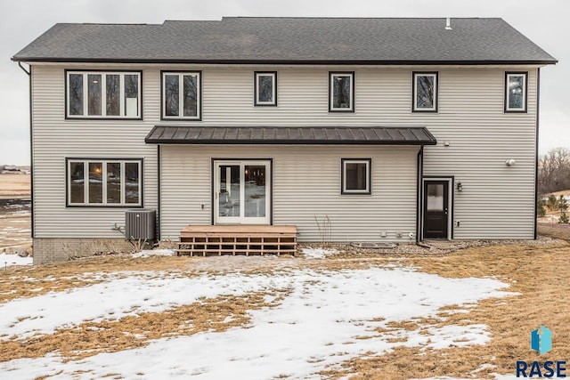 snow covered property with french doors, metal roof, and central AC unit