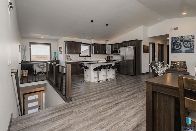 23744 461a Ave # 2, Wentworth, SD 57075 - kitchen with vaulted ceiling, a kitchen island, visible vents, wood finished floors, and stainless steel appliances