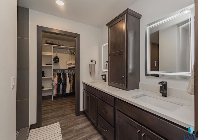 23744 461a Ave # 2, Wentworth, SD 57075 - bathroom featuring a sink, a walk in closet, double vanity, and wood finished floors
