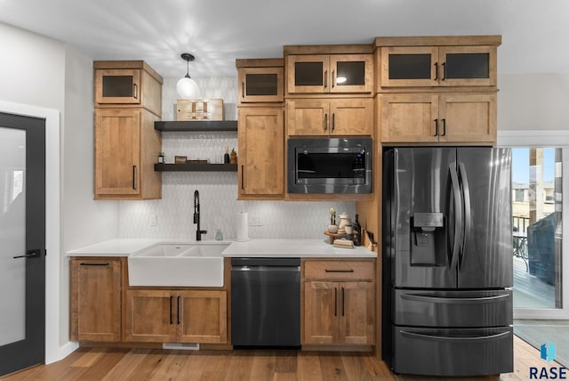 kitchen with a sink, open shelves, appliances with stainless steel finishes, and brown cabinets