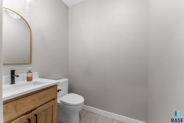 half bath featuring toilet, vanity, baseboards, and tile patterned flooring