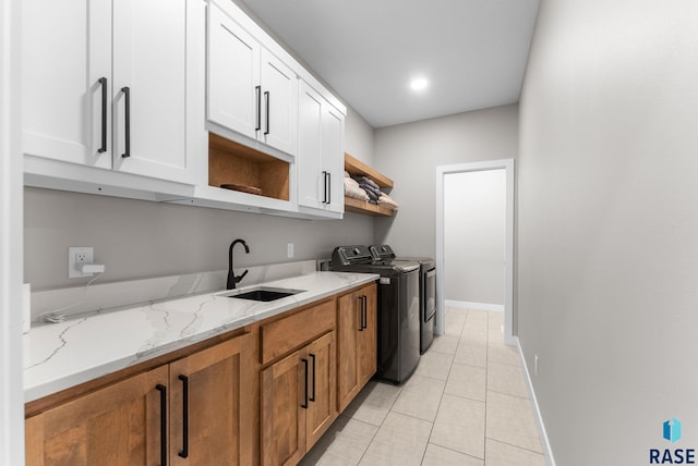kitchen featuring baseboards, light stone counters, open shelves, washer and clothes dryer, and a sink