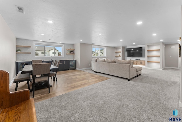 living area with visible vents, baseboards, light wood finished floors, recessed lighting, and light colored carpet