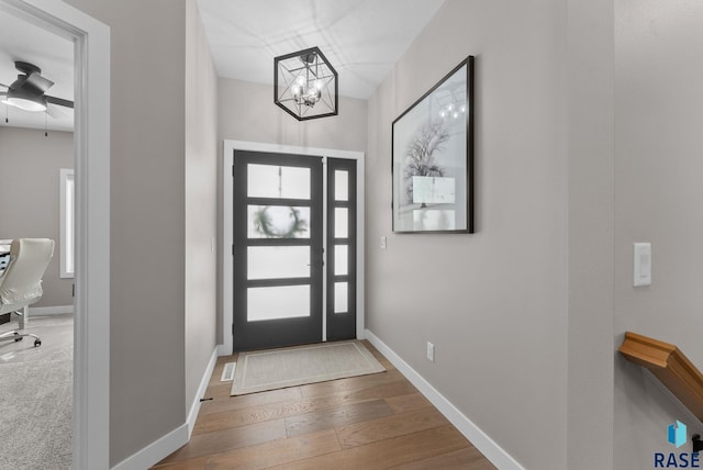 entryway with baseboards, hardwood / wood-style floors, and ceiling fan with notable chandelier