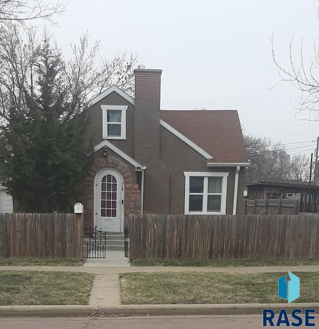 view of front of home featuring entry steps, stucco siding, a chimney, and a fenced front yard