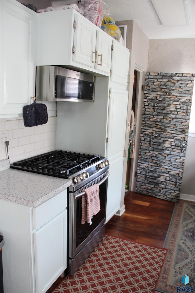 kitchen featuring white cabinets, tasteful backsplash, stainless steel appliances, and light countertops