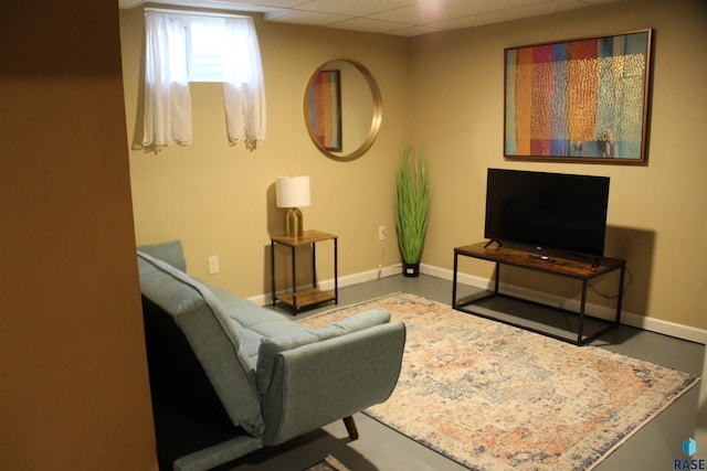 living area with baseboards and a paneled ceiling