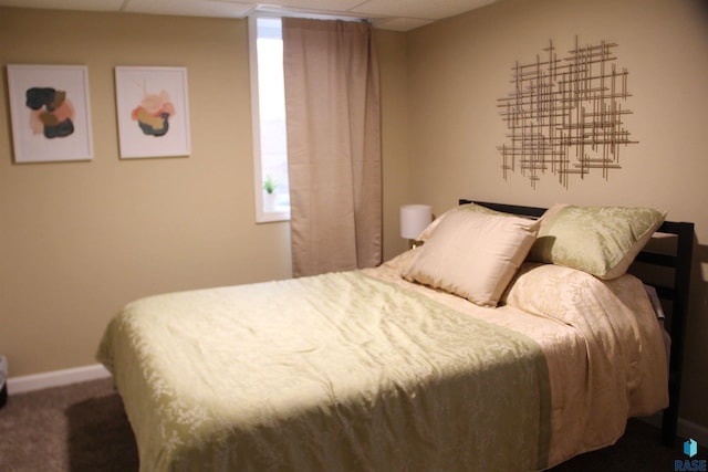 carpeted bedroom with a paneled ceiling and baseboards