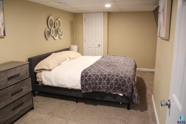 carpeted bedroom with baseboards and a paneled ceiling
