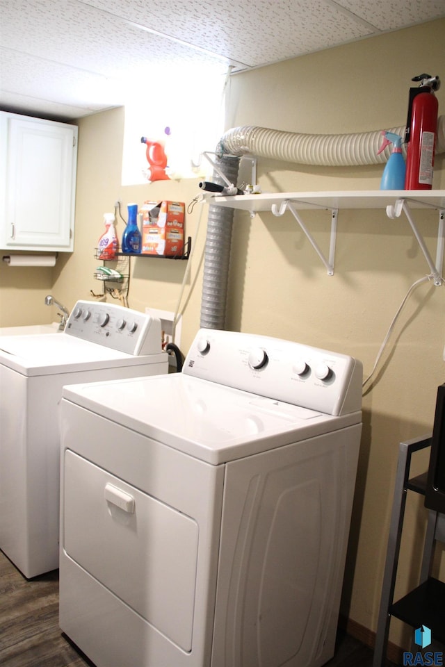 clothes washing area featuring washing machine and clothes dryer, dark wood-style floors, and cabinet space