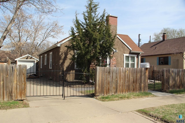 view of front of home with stucco siding, a chimney, a gate, and a fenced front yard