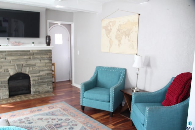 sitting room with arched walkways, baseboards, wood finished floors, and a fireplace