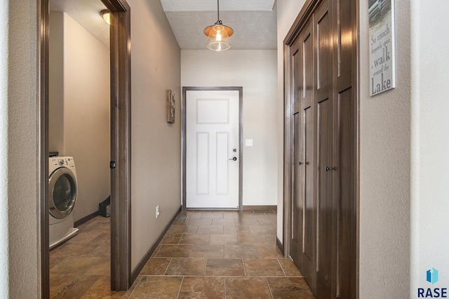 hall with washer / clothes dryer, baseboards, and stone finish floor