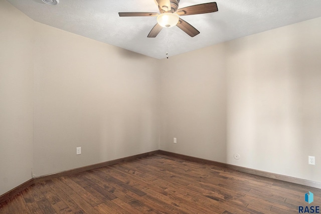 unfurnished room featuring dark wood-style flooring, ceiling fan, and baseboards