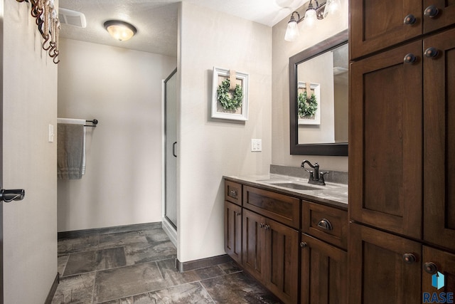 full bathroom with a shower stall, vanity, baseboards, and stone finish flooring