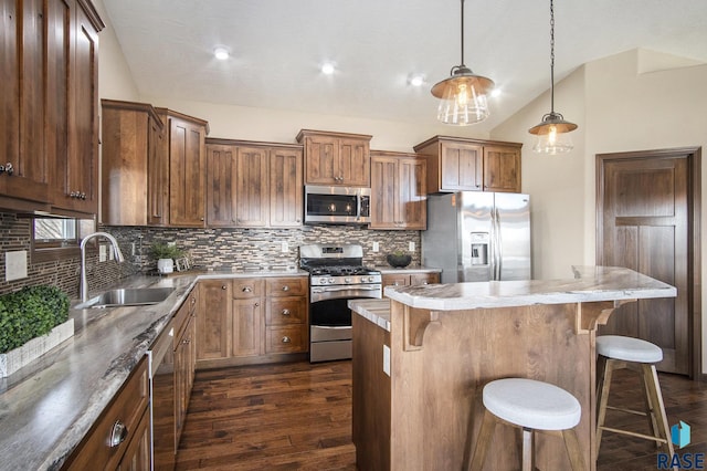kitchen with appliances with stainless steel finishes, dark wood-style flooring, vaulted ceiling, decorative backsplash, and a sink