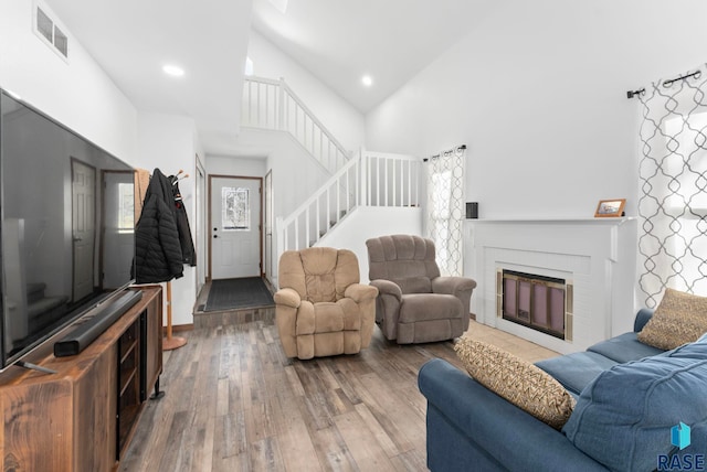 3325 E Manor Cir, Sioux Falls, SD 57103 - living room with high vaulted ceiling, visible vents, stairway, a brick fireplace, and hardwood / wood-style flooring