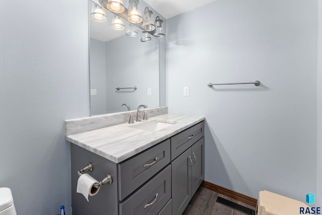 3325 E Manor Cir, Sioux Falls, SD 57103 - bathroom with visible vents, baseboards, toilet, vanity, and wood finished floors