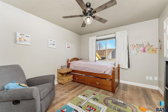 604 Eagle Ave, Harrisburg, SD 57032 - bedroom with light wood-style flooring, a textured ceiling, ceiling fan, and baseboards
