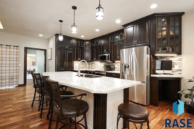 105 N Nora St, Viborg, SD 57070 - kitchen featuring decorative light fixtures, a sink, appliances with stainless steel finishes, wood finished floors, and backsplash