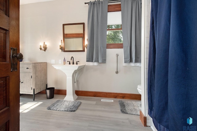 28128 462nd Ave, Davis, SD 57021 - bathroom with toilet, curtained shower, wood finished floors, and baseboards