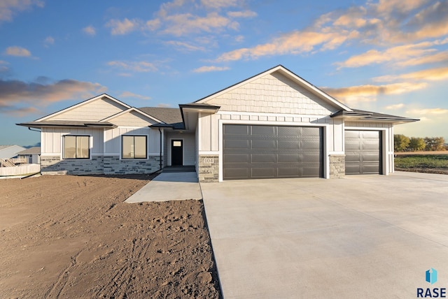 view of front of house with concrete driveway, board and batten siding, stone siding, and an attached garage