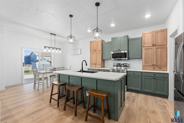 kitchen featuring a sink, light wood-style flooring, green cabinetry, and stainless steel appliances