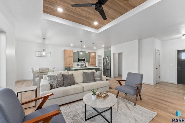 living area with a tray ceiling, baseboards, a ceiling fan, and wooden ceiling