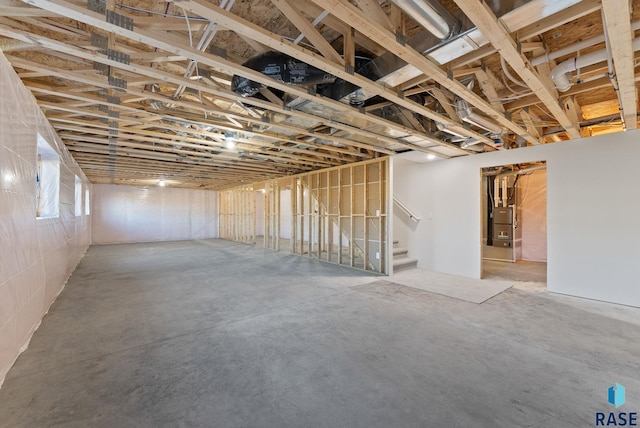 basement featuring stairway and heating unit