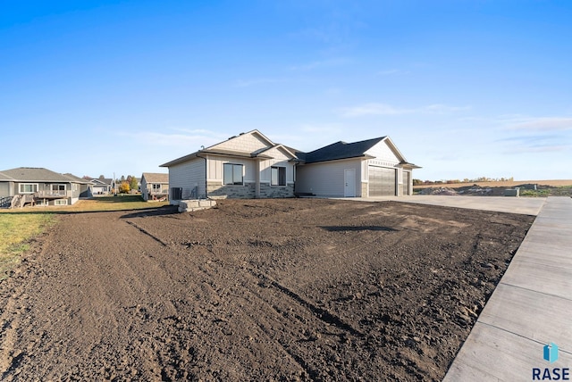 ranch-style home with driveway, stone siding, and a garage